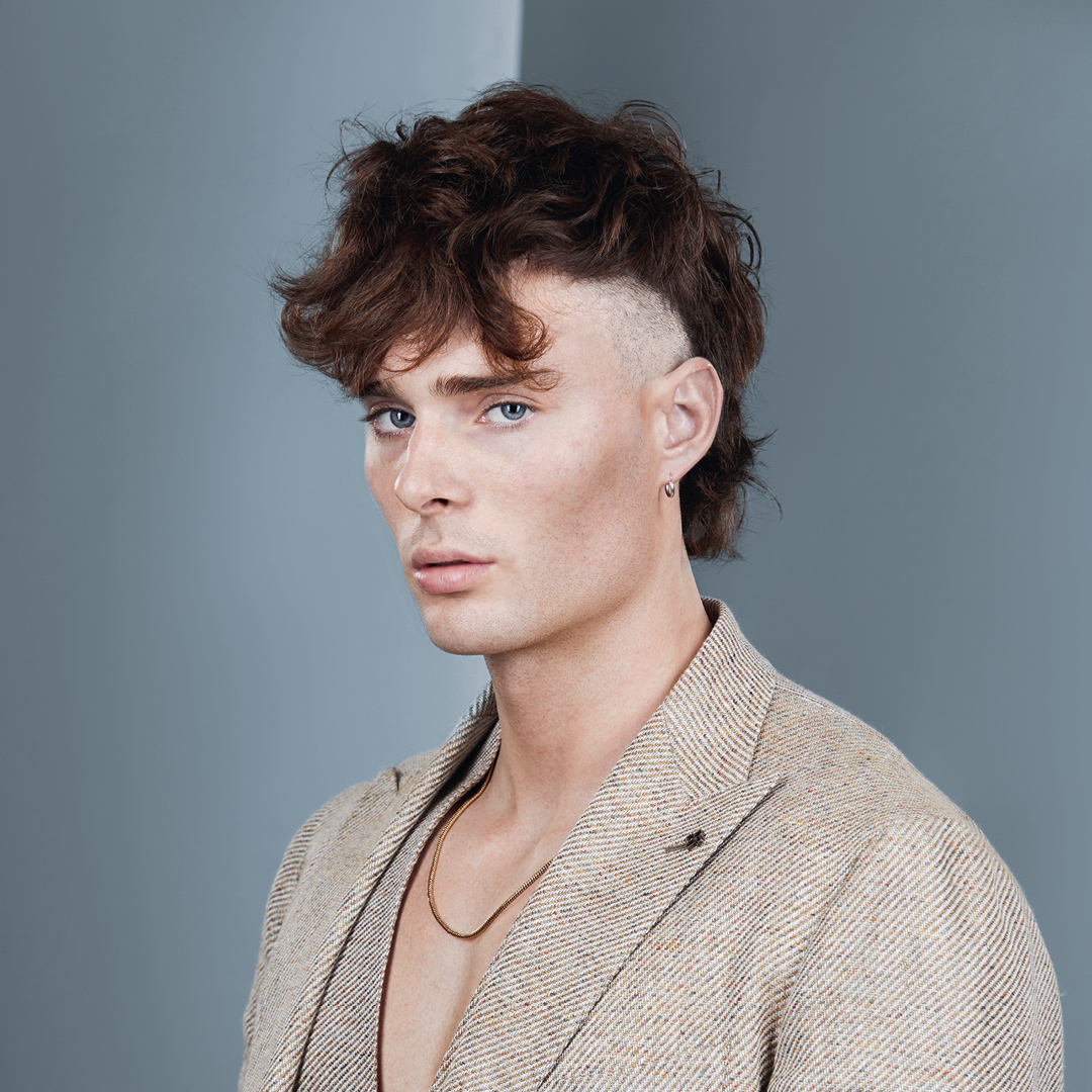 immagine ragazzo con giacca grigia, capelli con mullet molto rasato ai lati